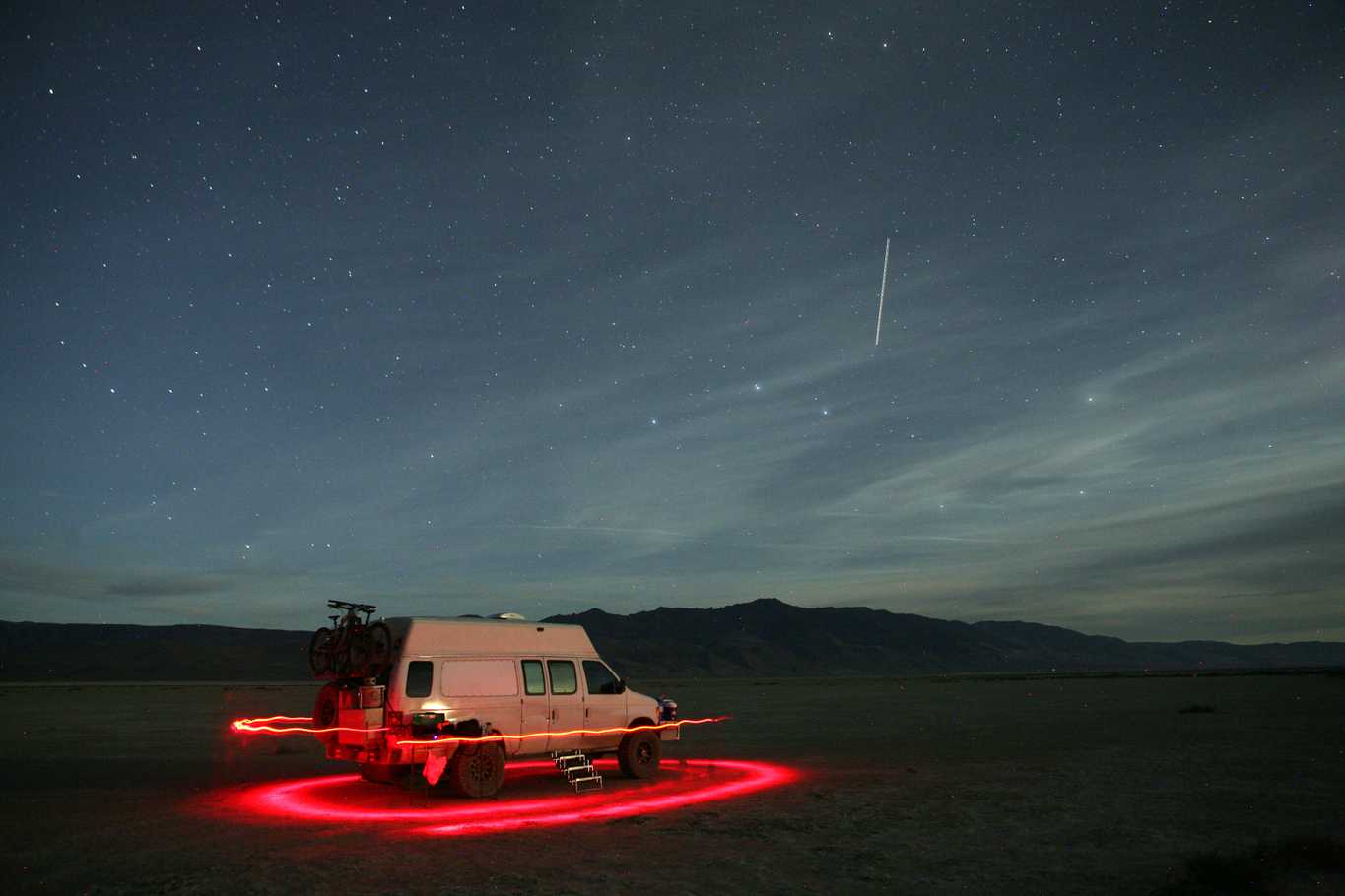 The night sky at the Alvord Desert with our van encircled by a red headlamp in a long exposure