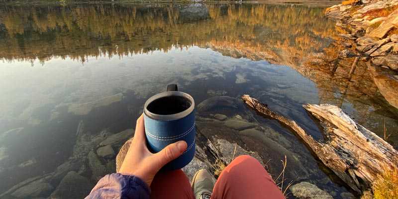 Sitting at a remote lake with yellow larches at sunrise and my camping cup in my hand.