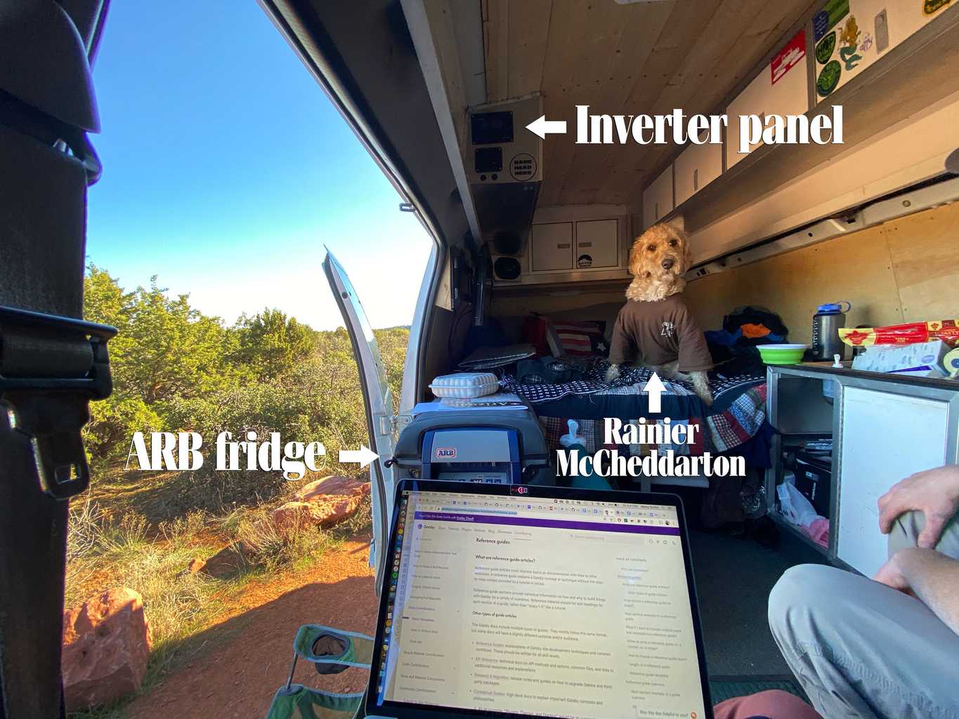 The inside of our van with the doors and windows open, with Rainier the labradoodle on the bed and my laptop in my lap